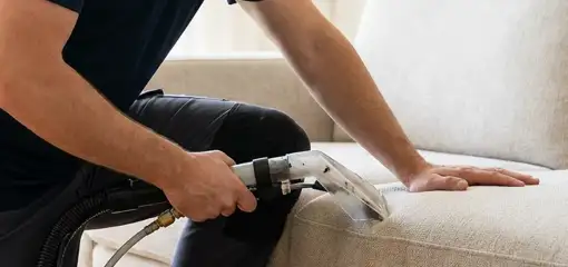 Professional upholstery cleaner deep-cleaning a fabric sofa with a handheld extraction tool, New Haven, CT.